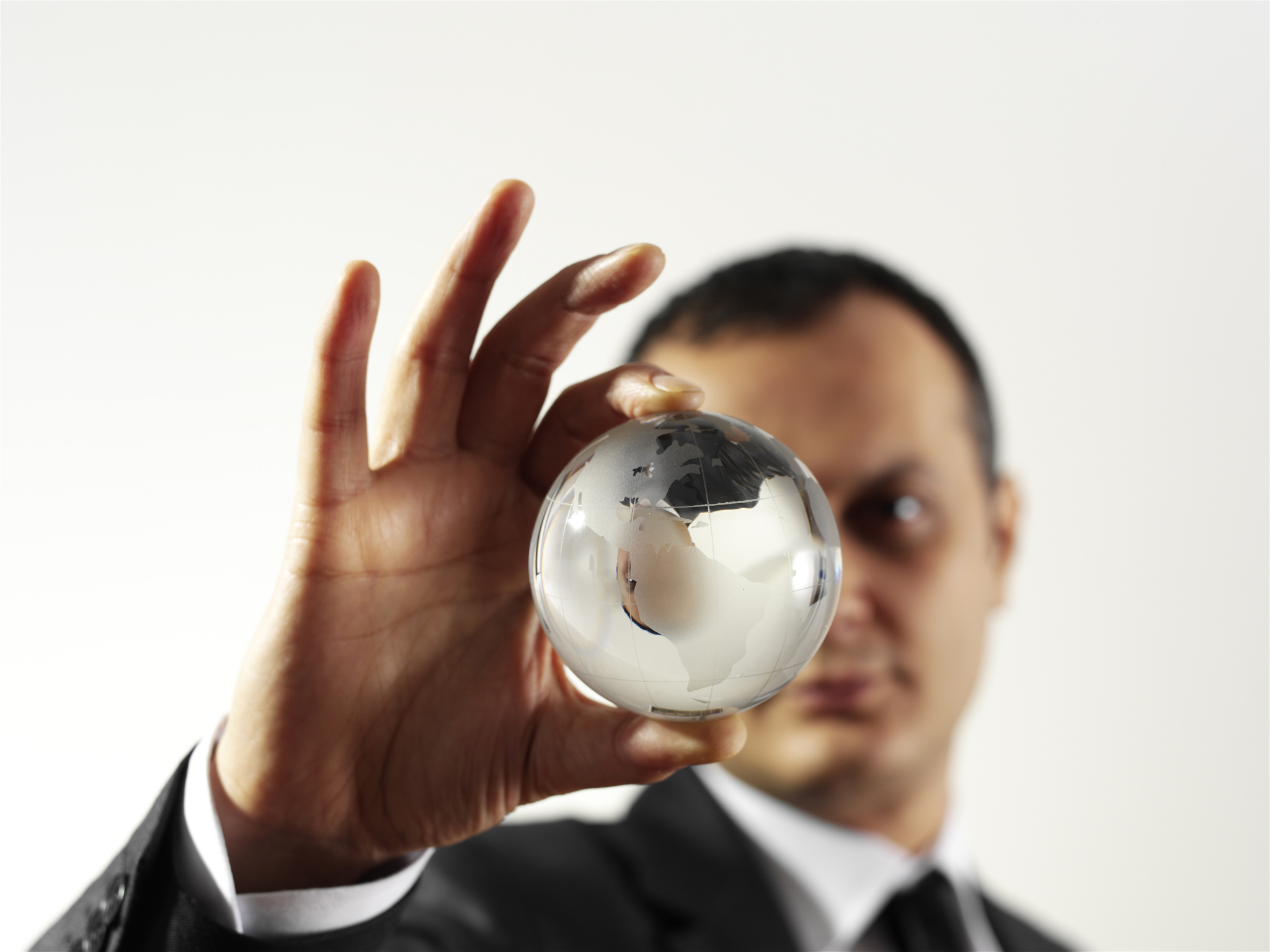 A man in a suit holding up a glass globe.