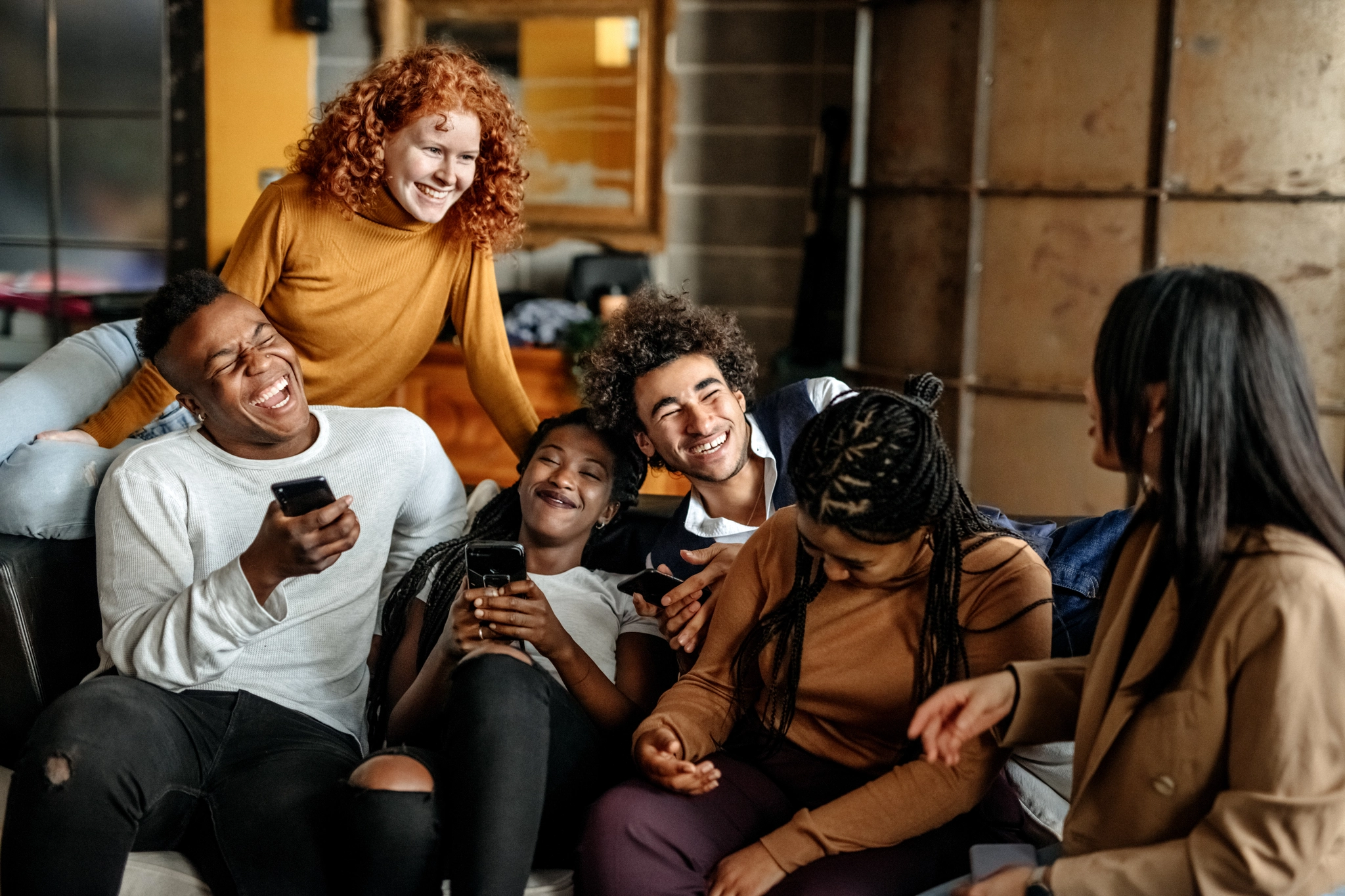 A group of friends engrossed in their phones while sitting on a couch.