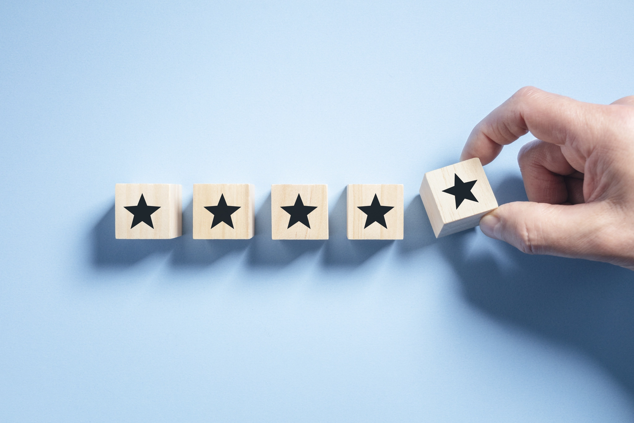 A person displays a wooden block with five stars, signifying top ratings and exceptional standards