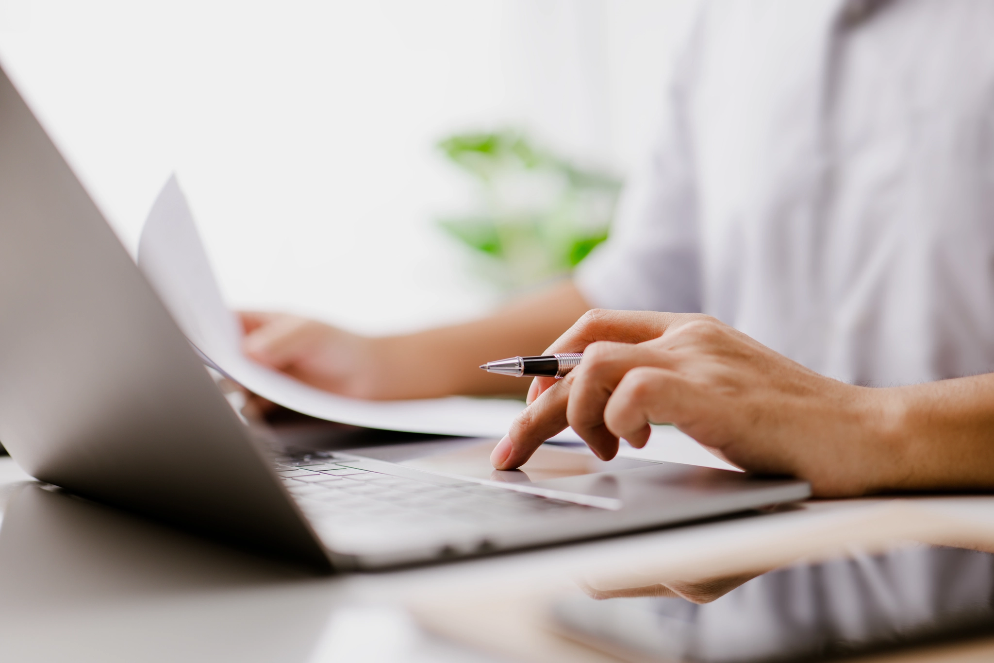 A person focused on typing on a laptop computer, with hands positioned over the keyboard.