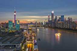 Urban skyline at night with illuminated buildings and city lights.