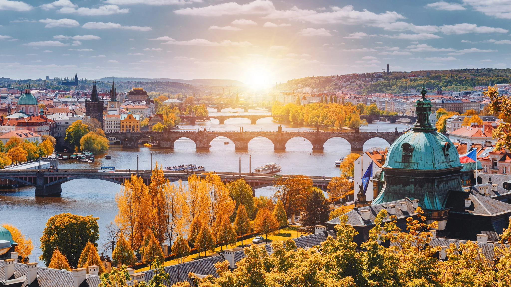 Bright sun illuminating Prague in autumn, highlighting the city's architecture and fall foliage.