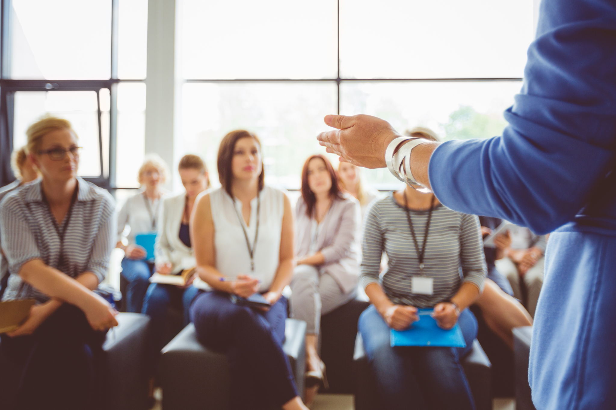 A person in a blue shirt speaking to a group of people