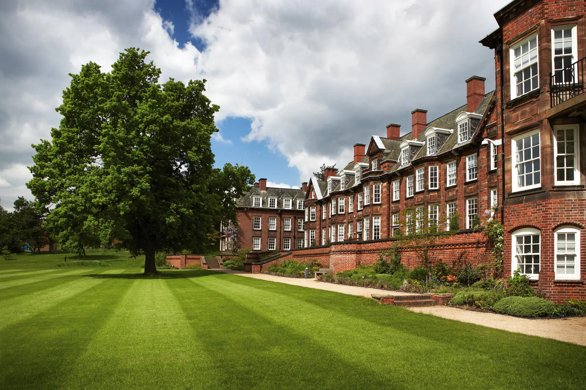 a large brick building with a lawn and a tree